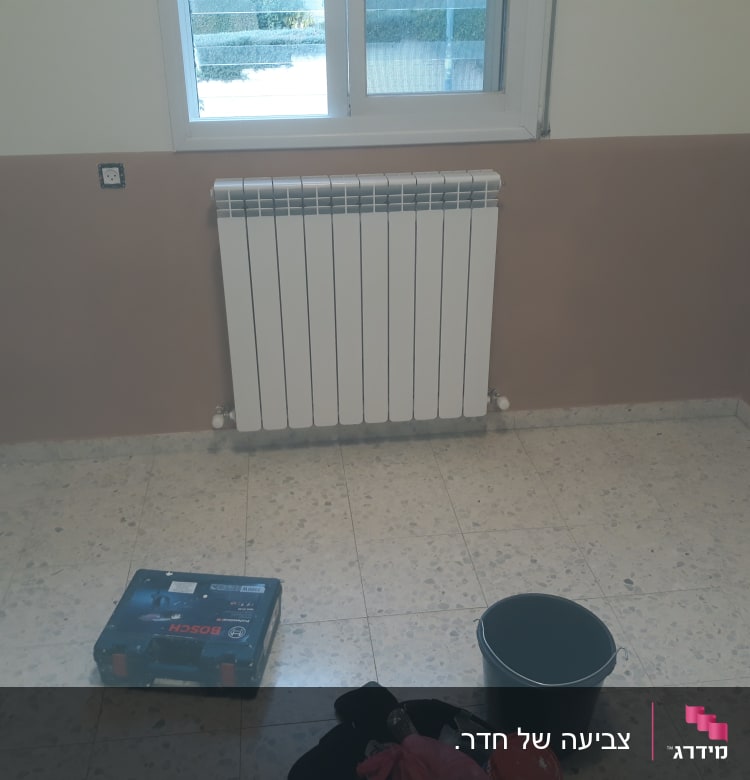 חדר עם קירות צבועים, דלי וצבע על הרצפה
